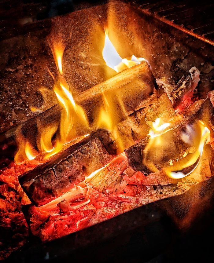 Close-up of a cozy fire with glowing logs and vibrant flames, evoking warmth and comfort.